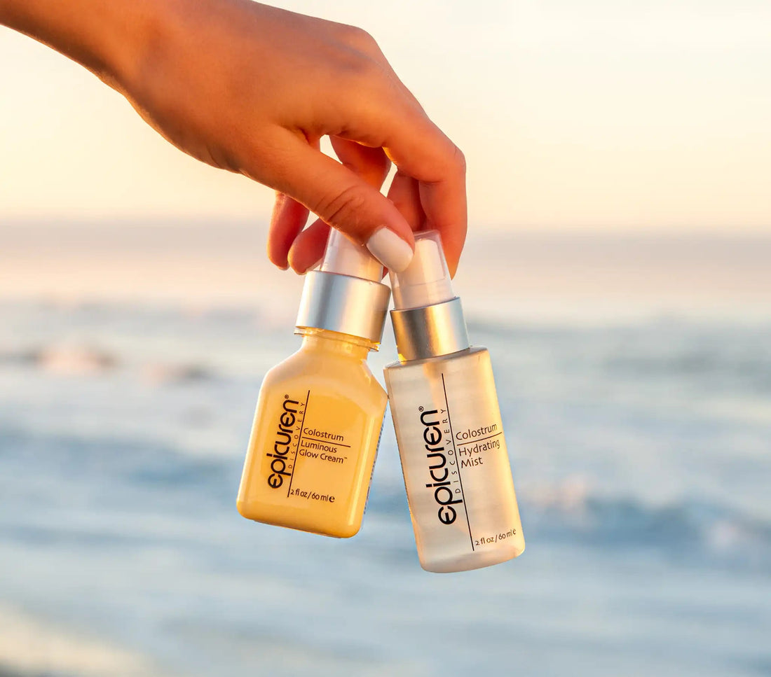 the Epicuren Colostrum Duo held by a hand against a beach sunset background.