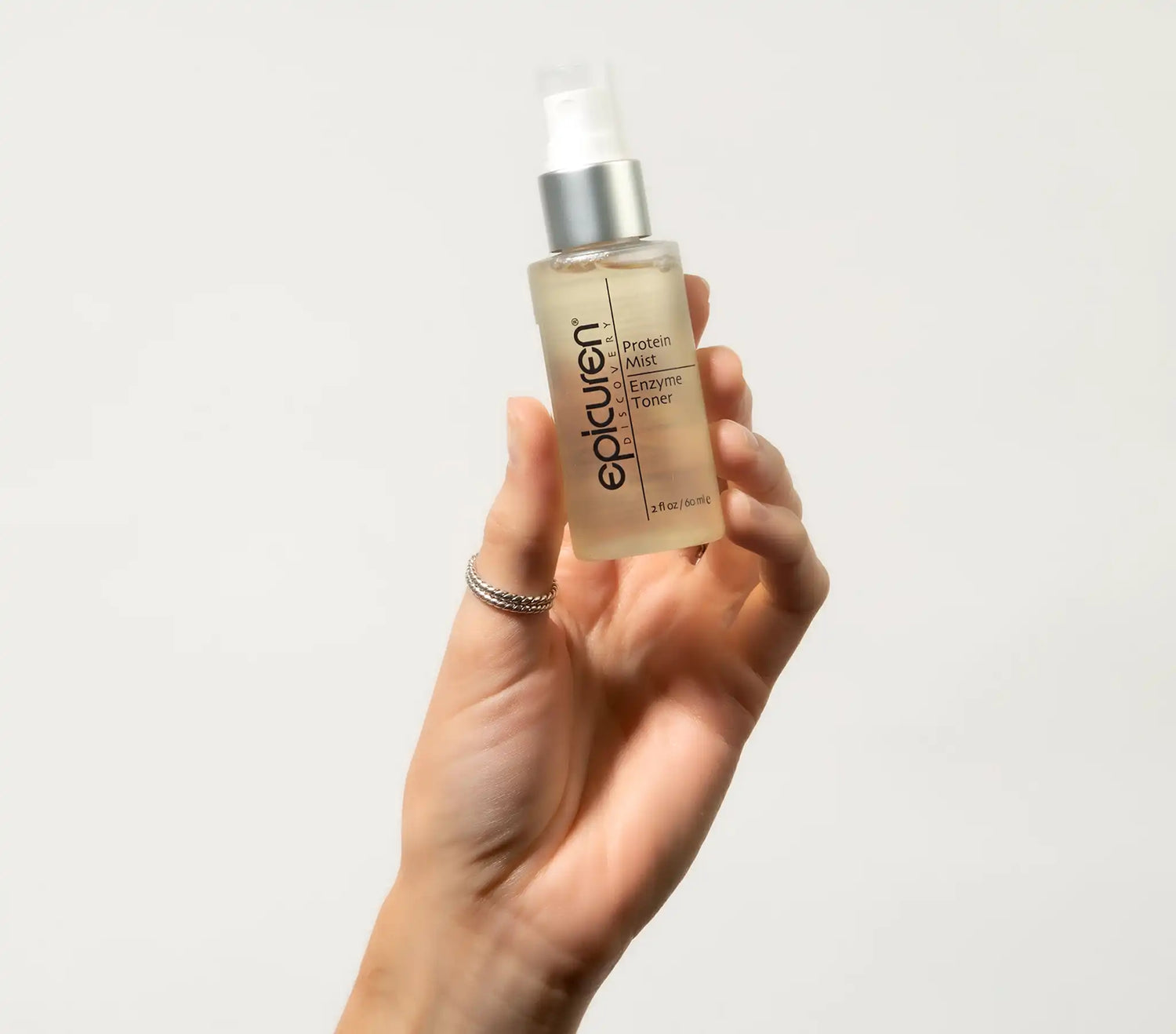 Hand holding a bottle of Epicuren Protein Mist Enzyme Toner against a plain background